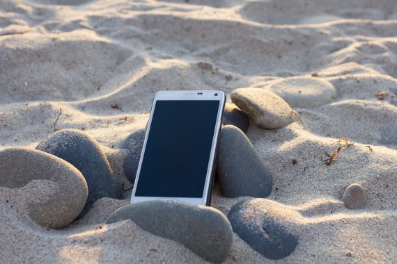 Smartphone liegt im Sand an einem Strand